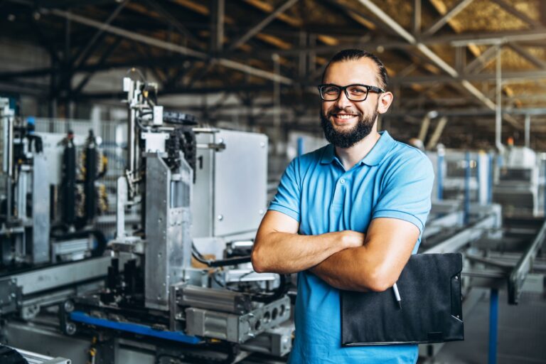 Young engineer manager with beard checking manufactory, workplace and machinery in big factory